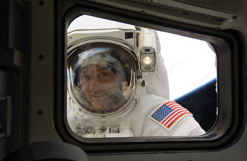 An astronaut peers in through a quartz window from space