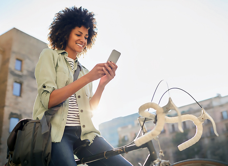 A woman sitting on a bike uses her smartphone