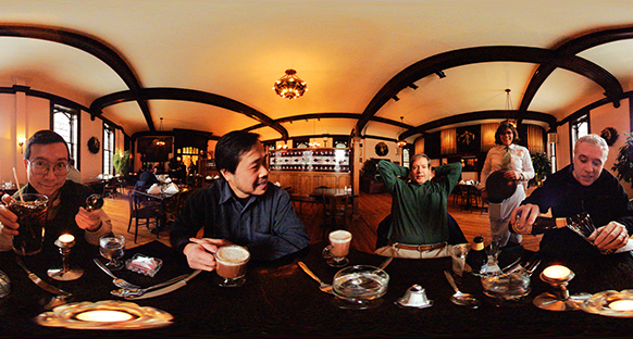 Wide photograph showing several people sitting together at a long table