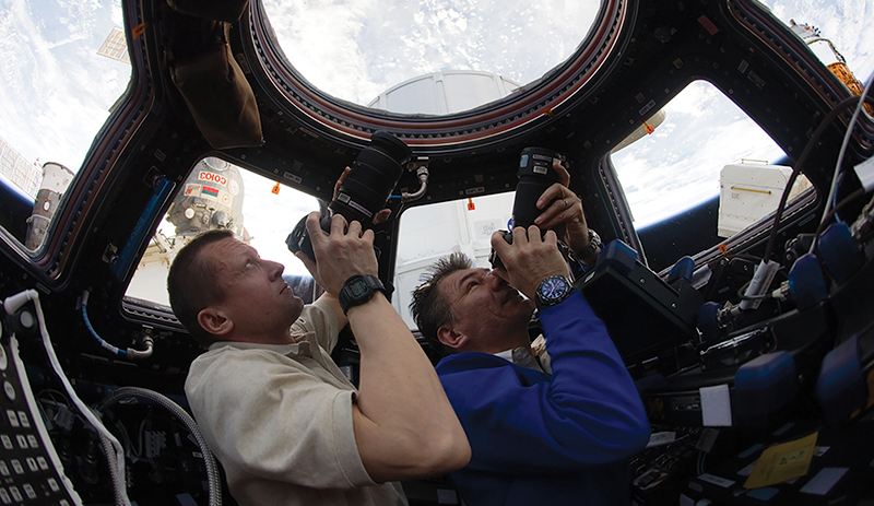 Russian cosmonaut Dmitri Kondratyev and Italian astronaut Paolo Nespoli take pictures of Earth from the ISS