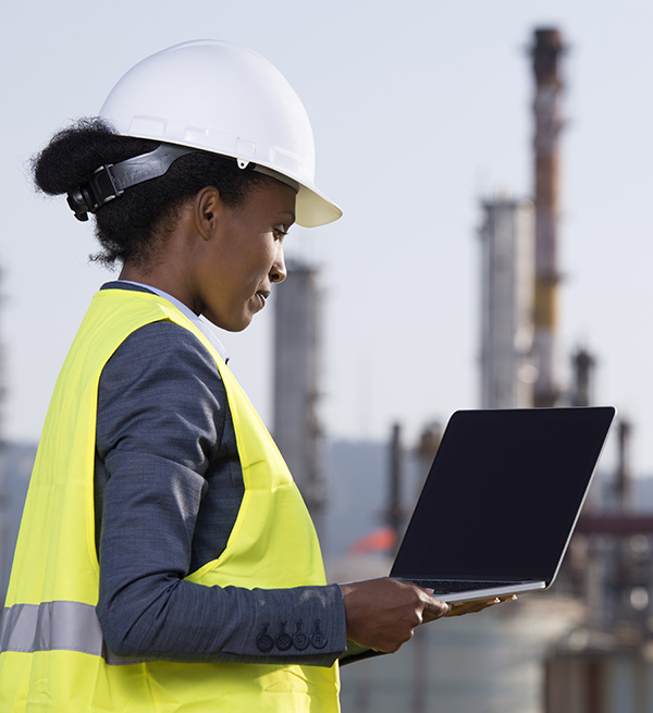 A worker uses a laptop in front of a power plant