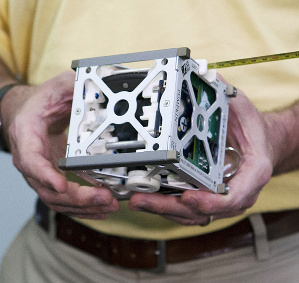 A CubeSat held in a man's hands