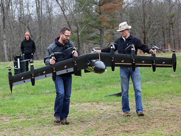 A battery-powered prototype drone, called Greased Lightning, carried by engineers David North (left) and Bill Fredericks (right)