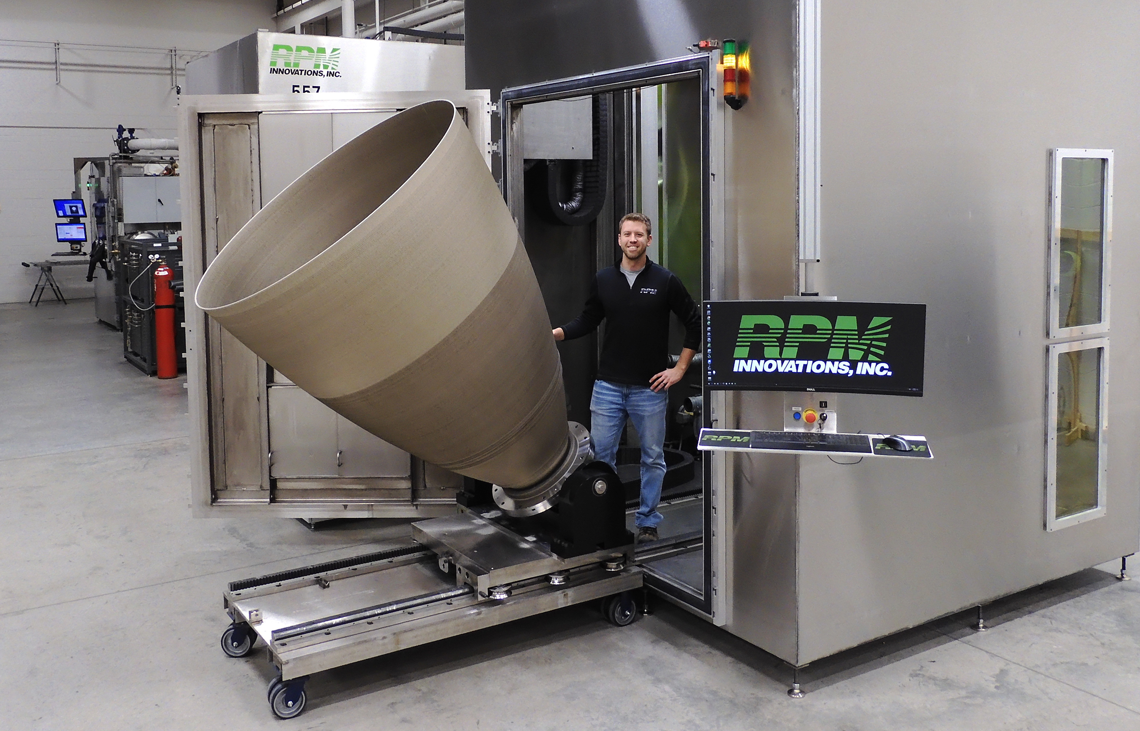 Tyler Blumenthal, sales manager at RPM Innovations, stands with a 3D printed rocket engine nozzle