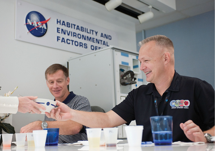 NASA astronauts Doug Hurley takes a bowl at a food tasting even at Johnson Space Center