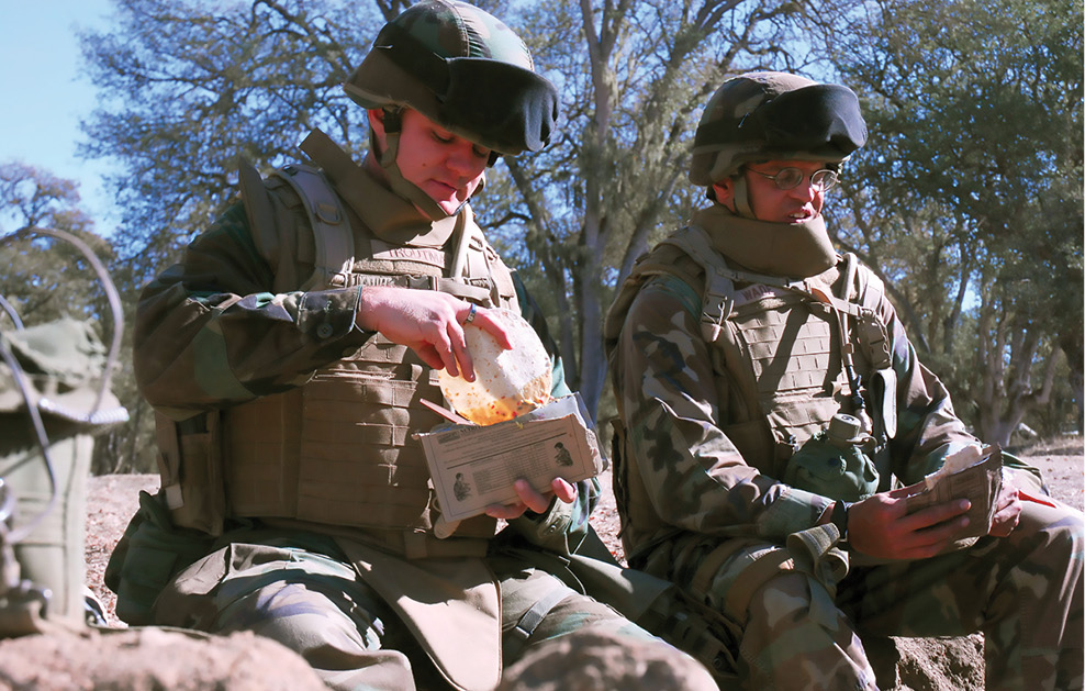 Two soldiers eat a packaged meal