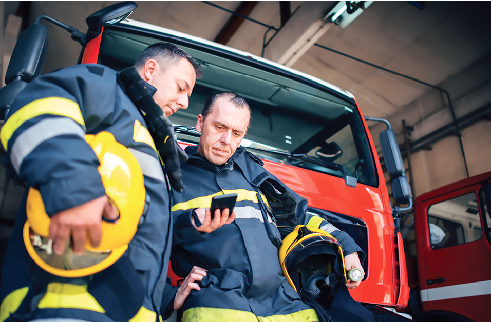 Two firefighters check a smartphone