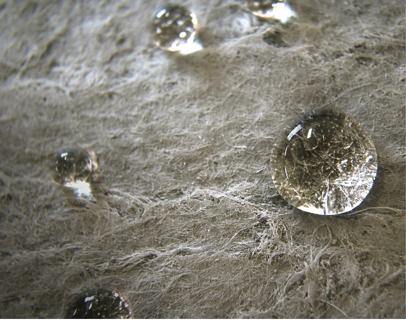 An extreme closeup of beads of water sitting on aerogel insulation