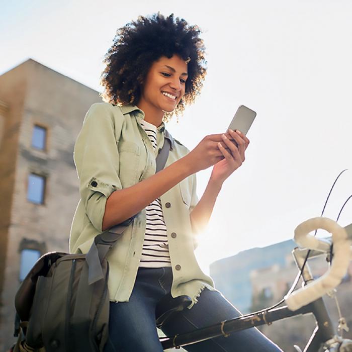 A woman sitting on a bike uses her smartphone