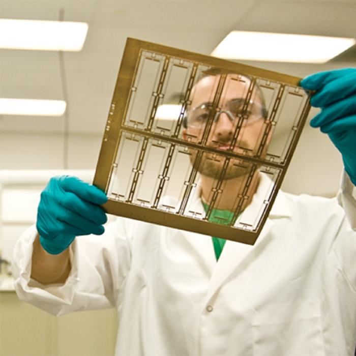 A Mikro Systems Inc. employee holds a layer of a TOMO tool.