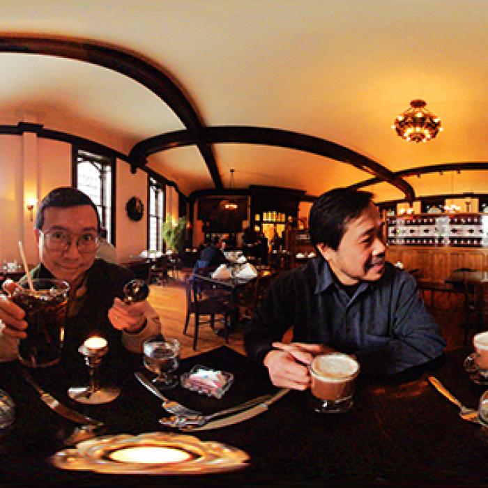 Wide photograph showing several people sitting together at a long table