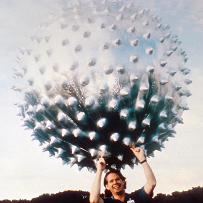 A man holding the Jimsphere, which looks like a large spiny metallic ball, above his head