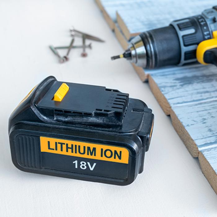 A lithium-ion 18-volt battery next to a cordless drill