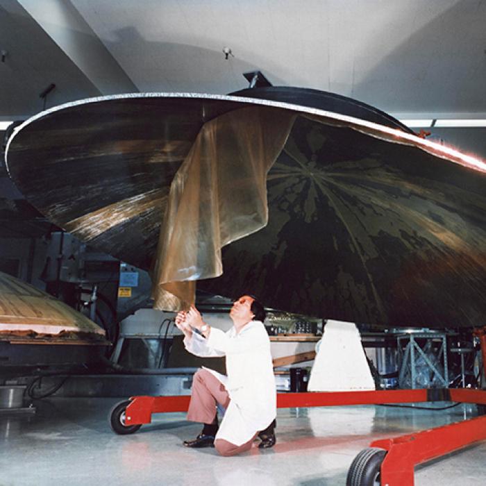 An engineer works on a Voyager spacecraft’s high-gain antenna dish