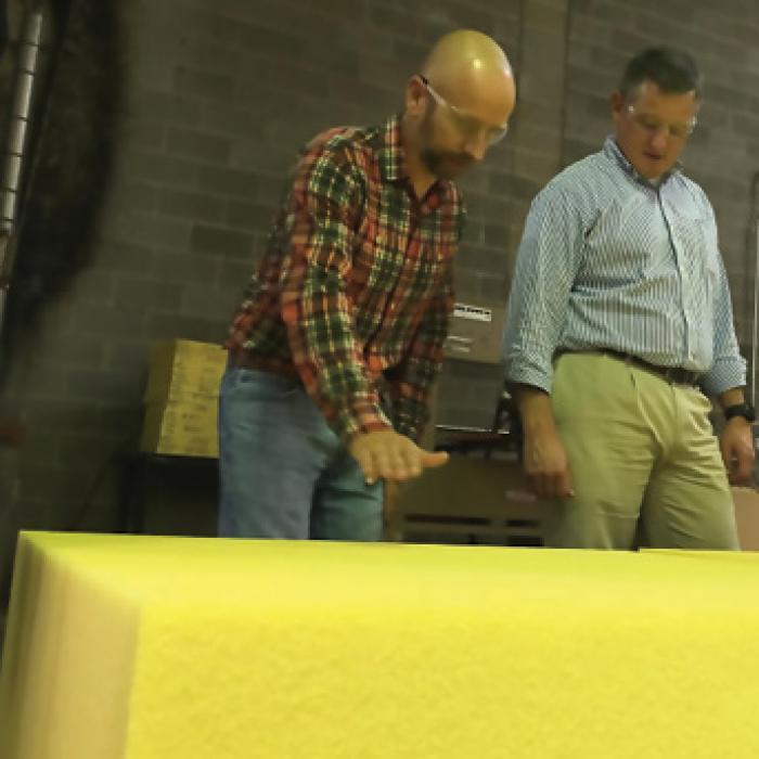 Boyd Corporation manager James Williams and local Congressman Bruce Westerman look at bright yellow Solimide panels