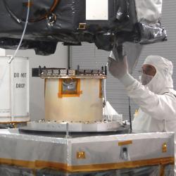 Engineer in clean room gear attaches spacecraft to separation device