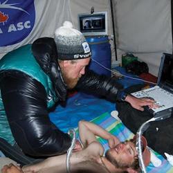 A mountain climber examines a colleague with ultrasound equipment.