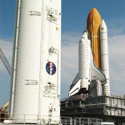 Space Shuttle Discovery on launch pad with large payload canister beside it