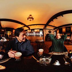 Wide photograph showing several people sitting together at a long table