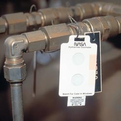 Badge hung on a pipe for use as a low-cost leak detector