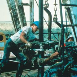 Workers at a Texaco oil field drill a vertical oil well