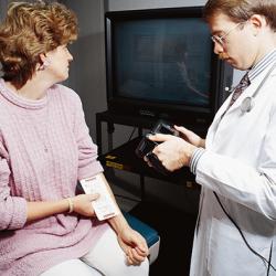 physician inspects a mole on patient's arm with a novel computerized microcomputer