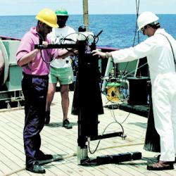 SeaSpec spectroradiometer on the deck of a ship with two men holding onto it and another man standing in background