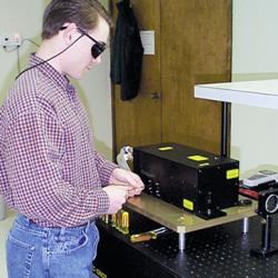 Worker wearing protective glasses and using a laser system