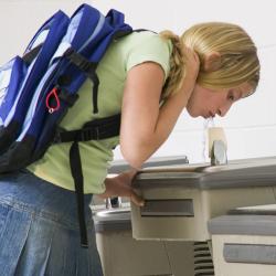 A student drinks from a school water fountain