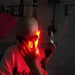 A doctor using a light-therapy device on a patient