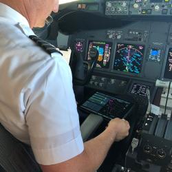 Alaska Airlines Captain Bret Peyton looks at route options presented on a tablet called an electronic flight bag