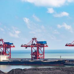 Three red steel structures on water behind black hills of a coal mine