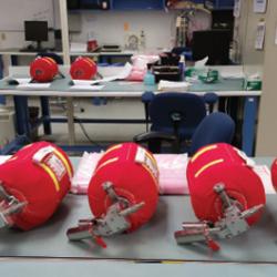 Red fire extinguishers lie in a row on a table in a lab